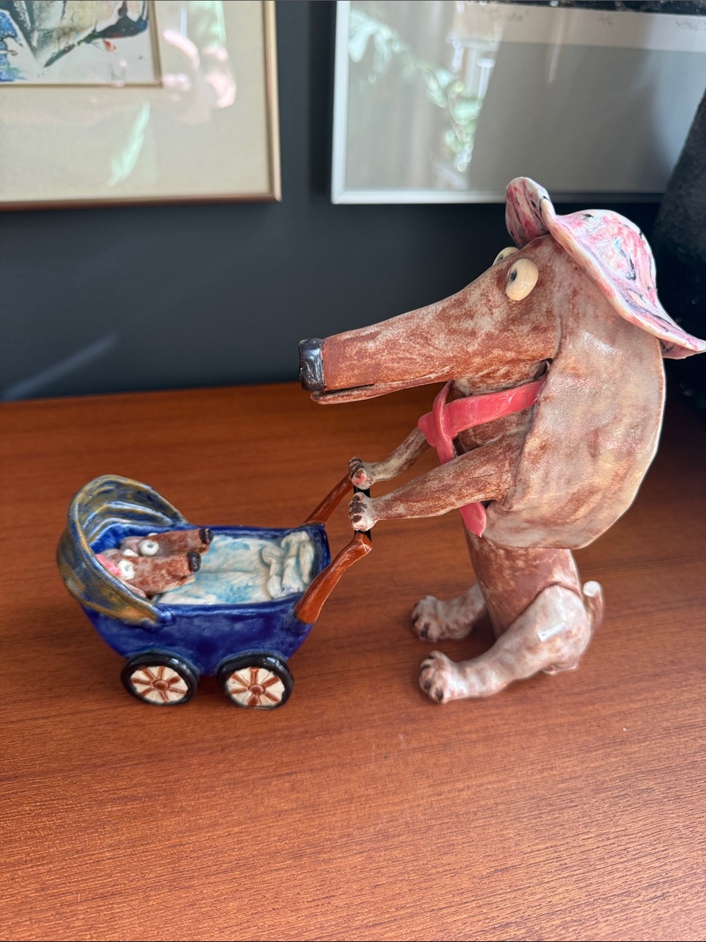 Hand Crafted Brown Dachshund Figurine Pushing Blue Carriage with Pink Hat